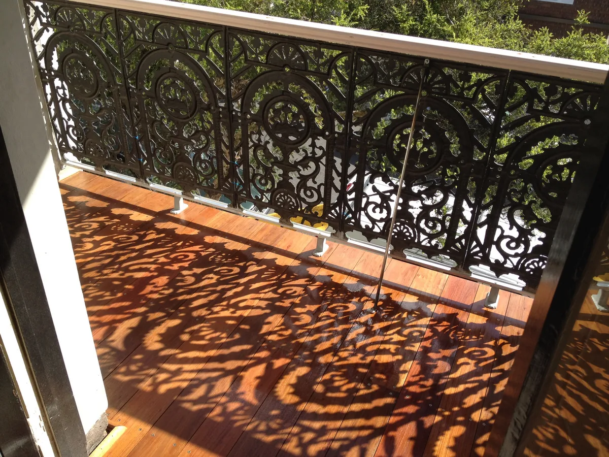 Restored timber balcony flooring beside decorative heritage ironwork