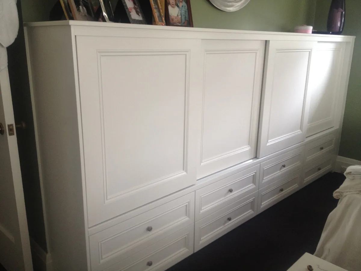 White storage cabinet beneath a window